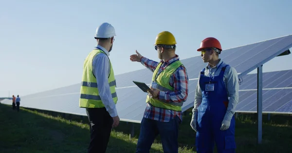 Trabajadores hablando entre largas filas de paneles solares —  Fotos de Stock