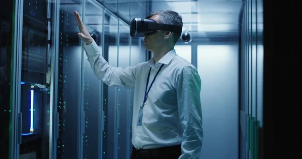 Técnico trabalha em um data center usando um fone de ouvido VR — Fotografia de Stock