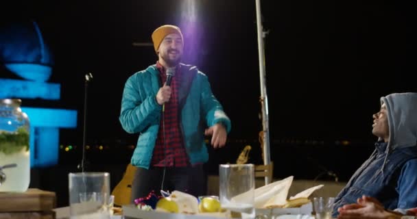Man at a rooftop party speaking on a microphone — Stock Video