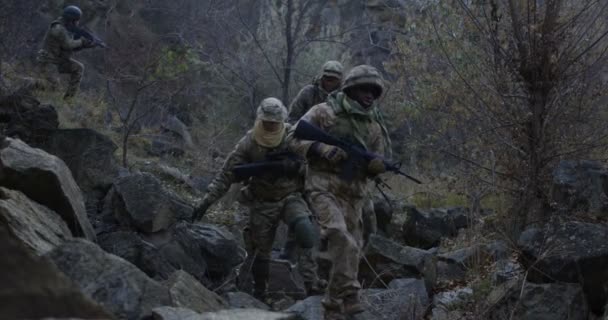 Soldats armés marchant dans les rochers au crépuscule — Video