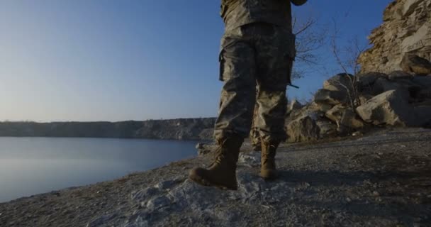 Bewaffnete Soldaten gehen an einem See entlang — Stockvideo