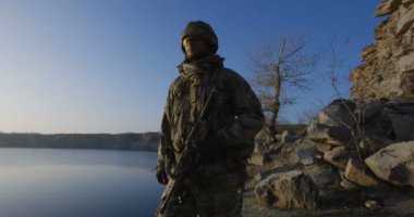 Silahlı askerler tek dosyada günbatımında yürüyüş