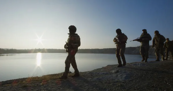 Soldaten marschieren bei Sonnenuntergang am See entlang — Stockfoto