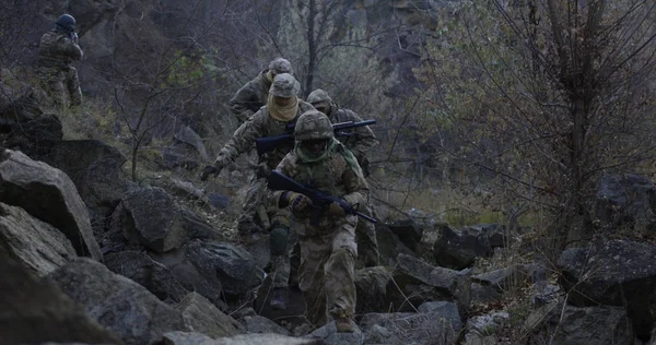 Bewaffnete Soldaten gehen in der Abenddämmerung durch Felsen — Stockfoto
