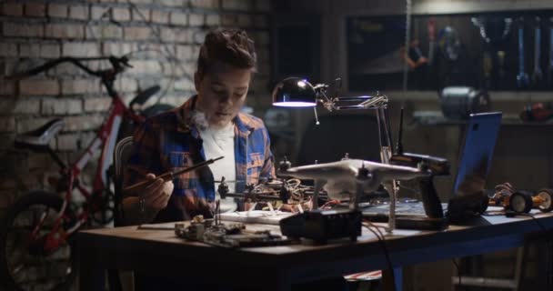 Мальчик ремонтирует и тестирует дрон — стоковое видео