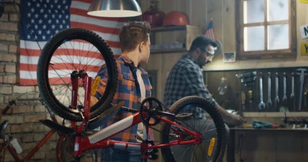 Pai e filho reparando uma bicicleta em uma garagem — Vídeo de Stock