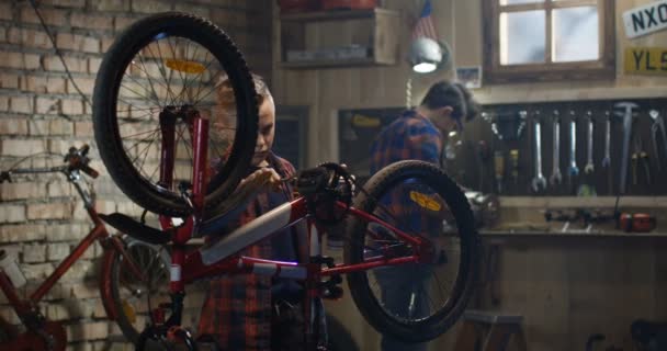 Zwei Jungen reparieren ein Fahrrad in einer Garage — Stockvideo