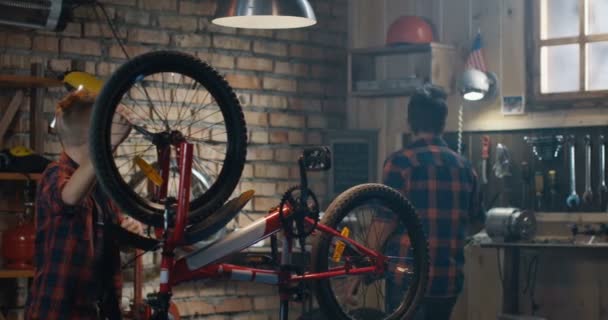 Dois meninos reparando uma bicicleta em uma garagem — Vídeo de Stock
