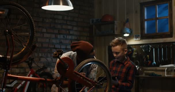 El hombre enseña a un niño mantenimiento de bicicletas — Vídeo de stock