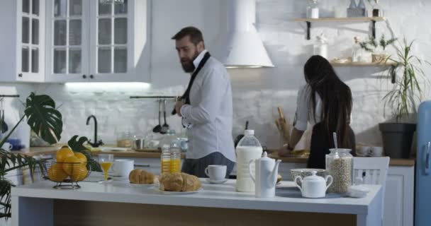 Муж присоединяется к жене на кухне на завтрак — стоковое видео
