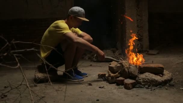 Чоловік дивиться на палаюче полум'я, сидячи один — стокове відео