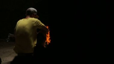 Kamp ateşi ile oturan genç adam