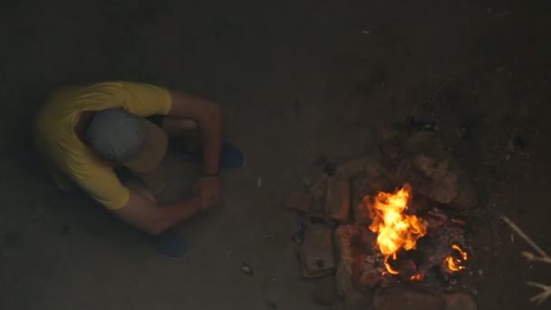 Joven sentado junto a la fogata — Vídeos de Stock