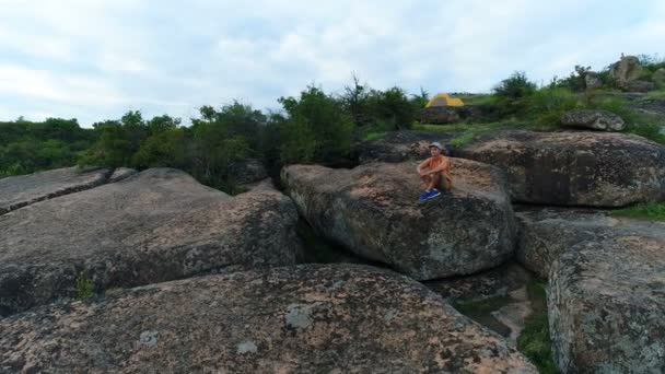 Giovane seduto su una roccia — Video Stock