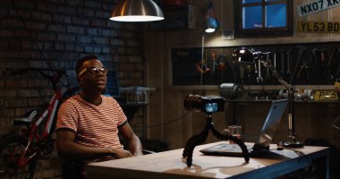 Bir garajda fotoğraf makinesinde konuşan genç adam