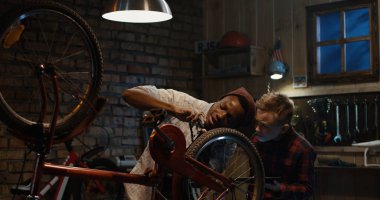 Adam bir çocuk bisiklet bakım öğretir.