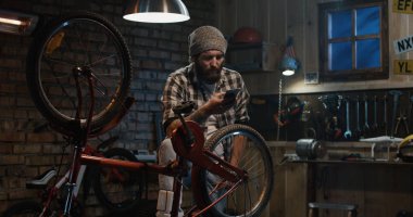 Atölyede akıllı telefon kullanan bir adam.