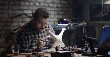 Bir adamın bir garaj bir dron tamir orta vurdu
