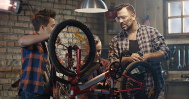 Baba ve iki oğlu bir bisiklet tamir