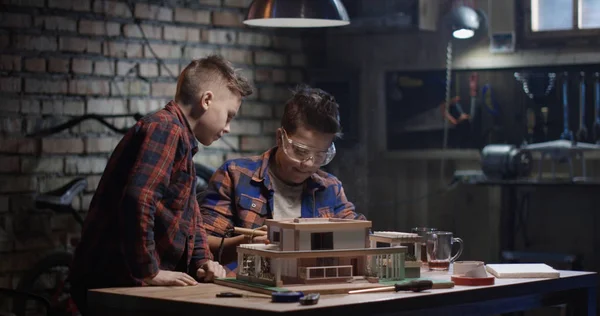 Dois meninos reparando uma casa modelo — Fotografia de Stock