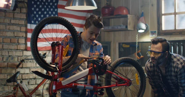 Padre e figlio riparano una bici in un garage — Foto Stock