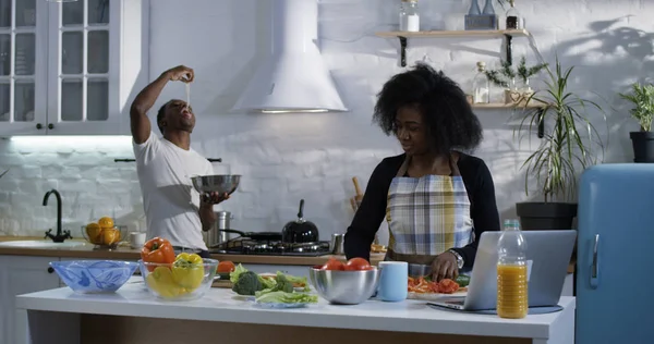 Jovem brincalhão provocando esposa na cozinha — Fotografia de Stock