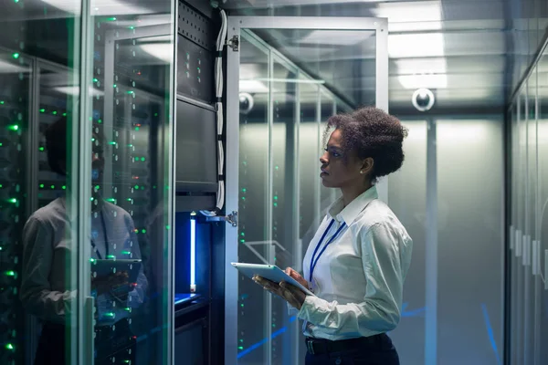 Técnico femenino trabaja en una tableta en un centro de datos — Foto de Stock