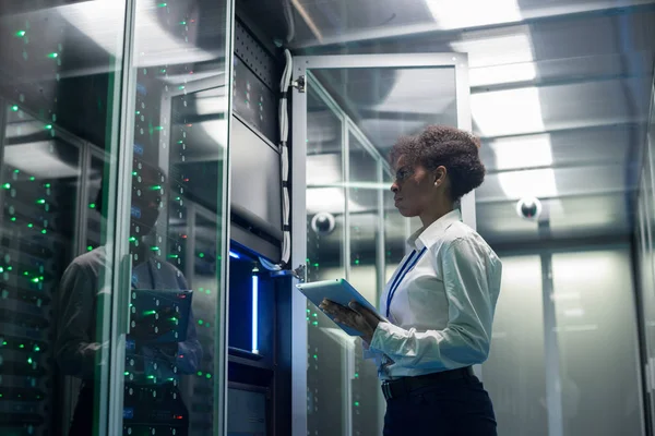 Female technician works on a tablet in a data center