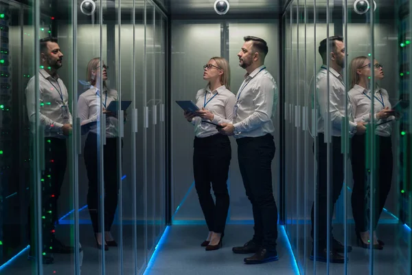 Trabajadores en un centro de datos caminando entre filas de bastidores de servidores — Foto de Stock