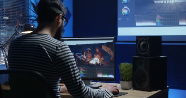 Joven sentado y editando vídeo dentro de una habitación — Vídeos de Stock