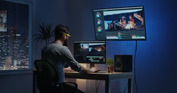 Joven sentado y editando vídeo dentro de una habitación — Vídeos de Stock