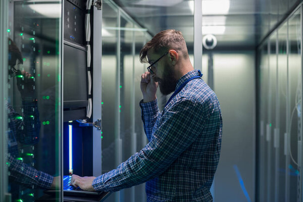 Bearded IT specialist setting servers in data center