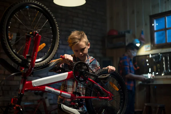 Two boys repairing a bike in a garage