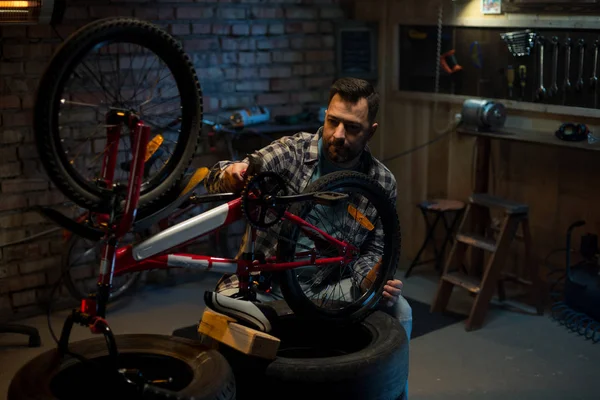 Uomo che lavora in una officina di riparazione di biciclette da solo — Foto Stock