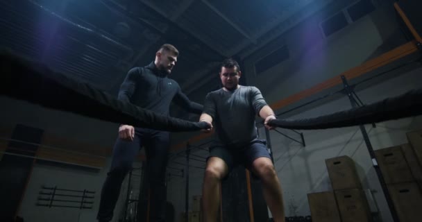 Entrenador que supervisa el entrenamiento de un joven con cuerda de batalla — Vídeo de stock