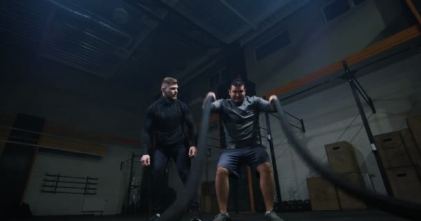 Treinador supervisionando jovem treinando com corda de batalha — Vídeo de Stock