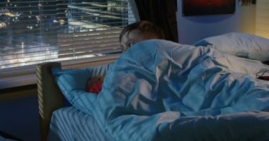 Erkek yatakta yalan pencereden dışarı bakıyor