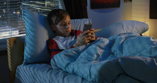 Boy textových zpráv při ležení v posteli — Stock fotografie
