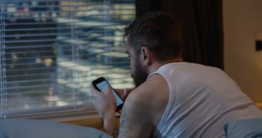 Yatakta cep telefonu kullanan adam