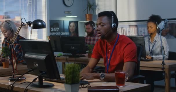 Tired man working at a support center — Stock Video