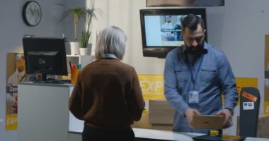 Bir teslimat merkezinde bir paket gönderen kadın