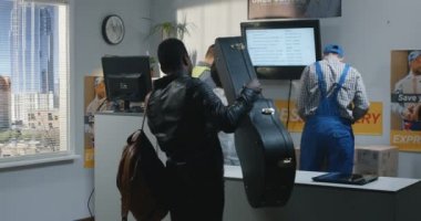 Bir teslimat merkezinde gitar çantası gönderen adam