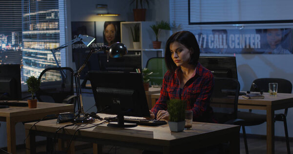 Молодая женщина, работающая ночью в офисе
