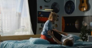 Çocuk ve kız yatakta yastık mücadele oynuyor