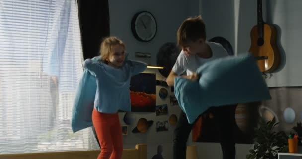 Garçon et fille jouer bataille d'oreiller sur le lit — Video