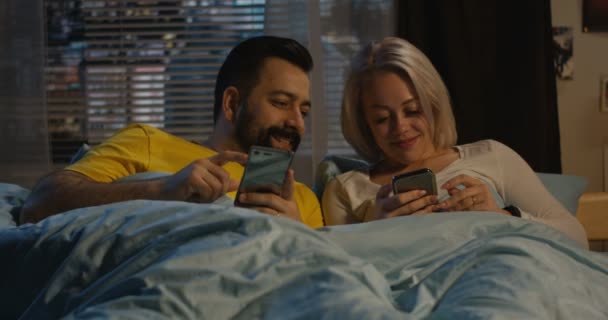 Ζευγάρι χρησιμοποιώντας το smartphone στο κρεβάτι — Αρχείο Βίντεο