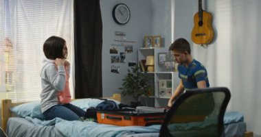 Kardeşler yatak odasında bir bavul paketleme