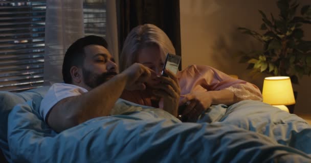 Paar gebruikend smartphone in bed — Stockvideo