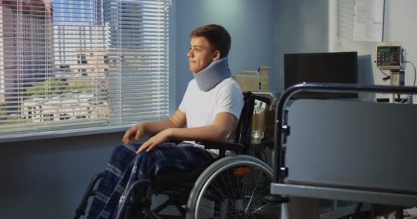 Hastanede tekerlekli sandalyede oturan genç hasta — Stok video