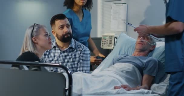 Paciente deitado no hospital entre os visitantes — Vídeo de Stock